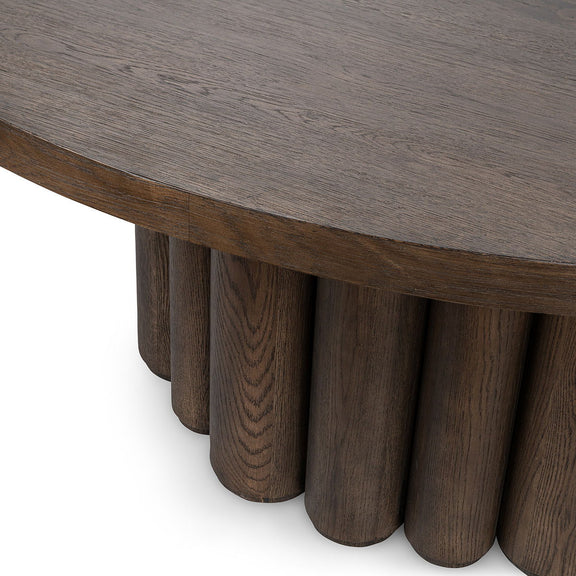 Toasted brown round dining table close-up of tabletop edge and fluted base.