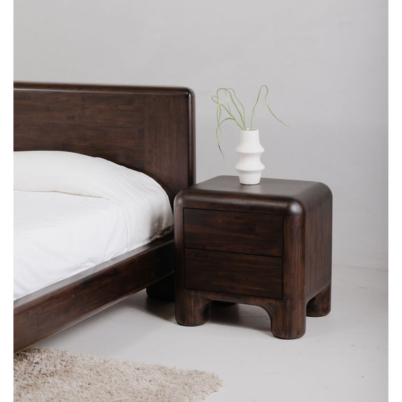 Dark brown wood nightstand with single drawer and rounded legs, small vase on top
