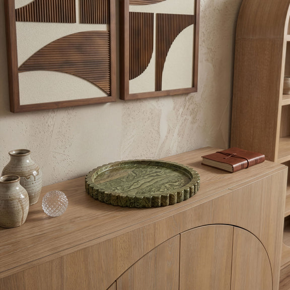 Round green marble tray on wooden console shelf with scalloped outer rim