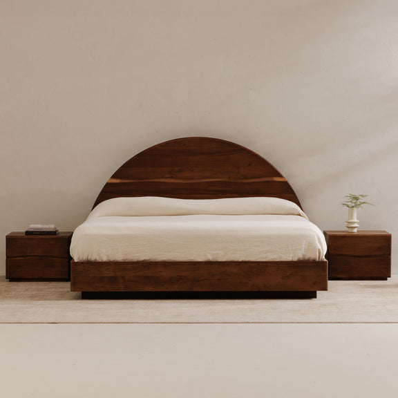 Brown king bed with arched headboard, white bedding, matching side tables
