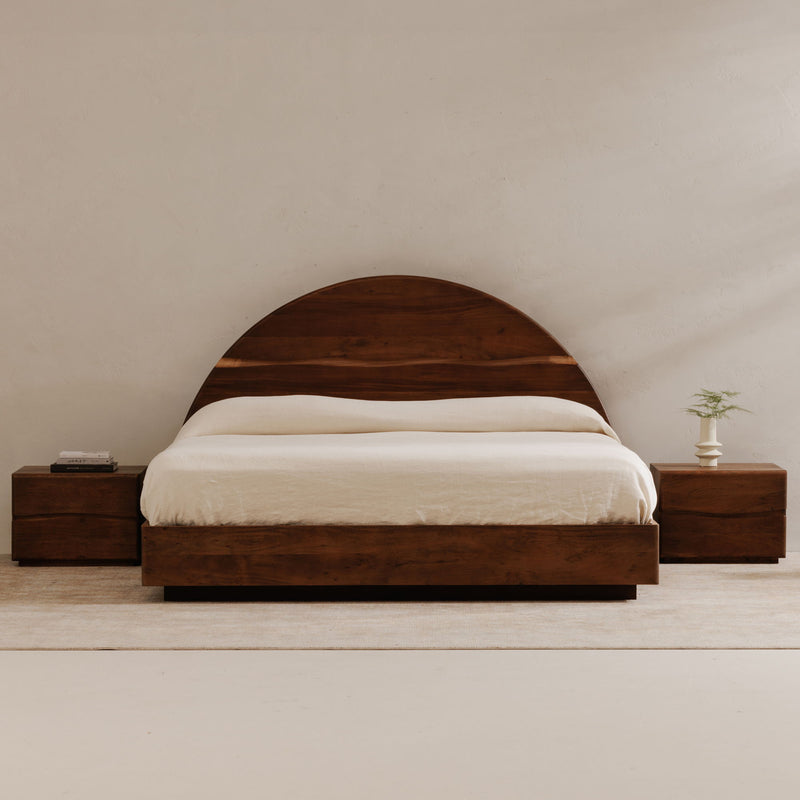Brown king bed with arched headboard, white bedding, matching side tables