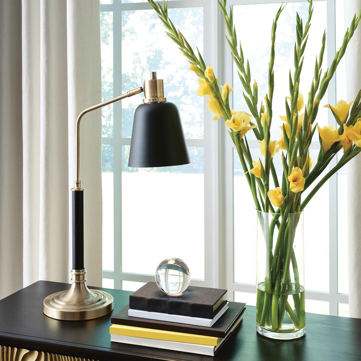 Metal lamp with black shade and brass-finish base on a tabletop