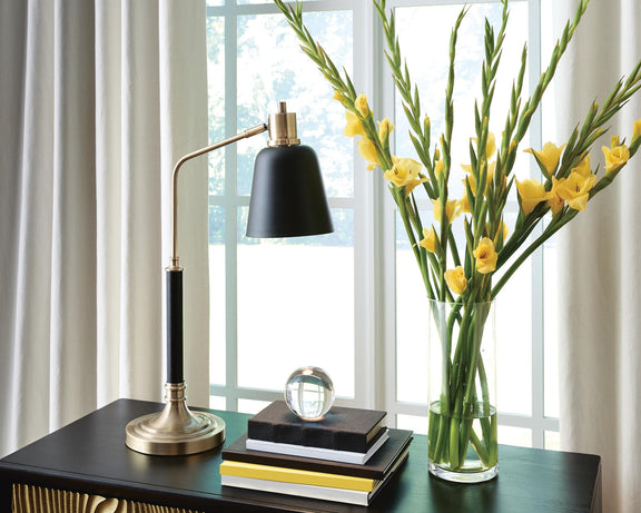 Metal lamp with black shade and brass-finish base on a tabletop