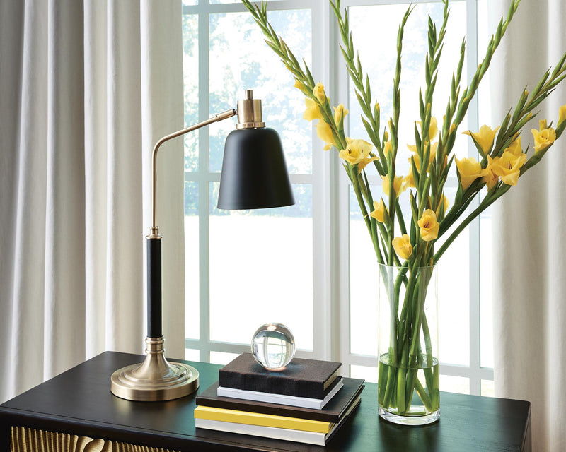 Metal lamp with black shade and brass-finish base on a tabletop