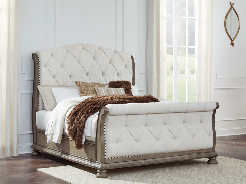 Tufted cream upholstered sleigh bed with low posts and dark wood trim