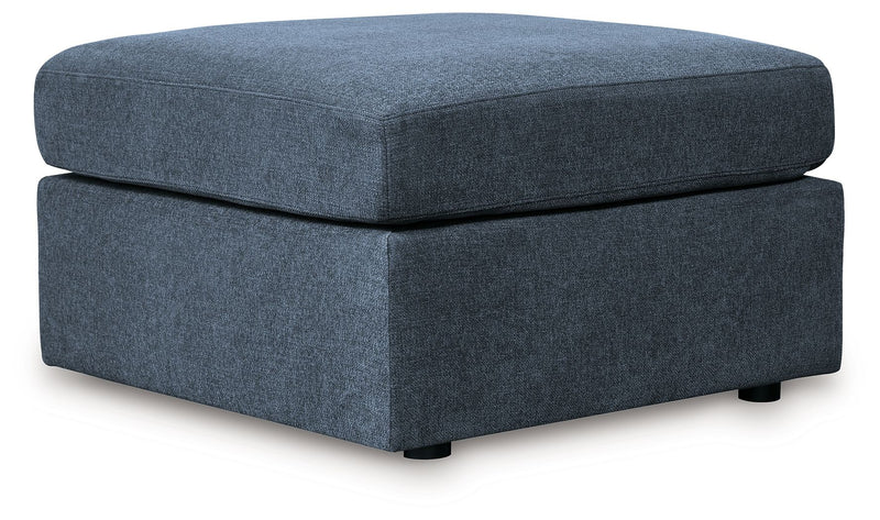 Square upholstered ottoman with dark blue fabric top and base, low legs