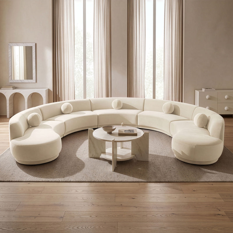 White velvet sectional sofa with rounded, button-tufted seat cushions in a room.