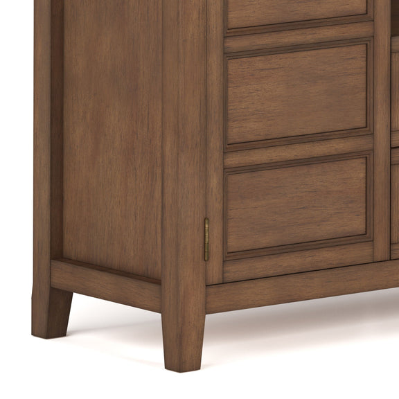 Corner view of tall TV media stand with wood panel doors and vertical cabinet trim