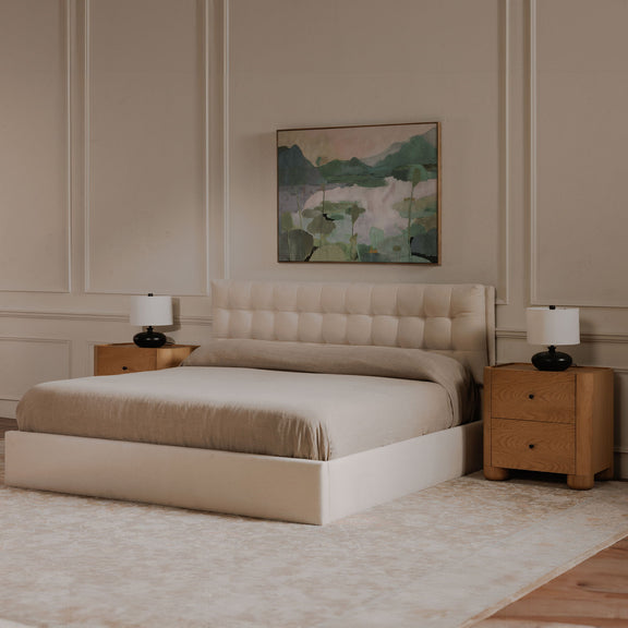 Cream upholstered king bed with tufted headboard, matching storage footboard, side view
