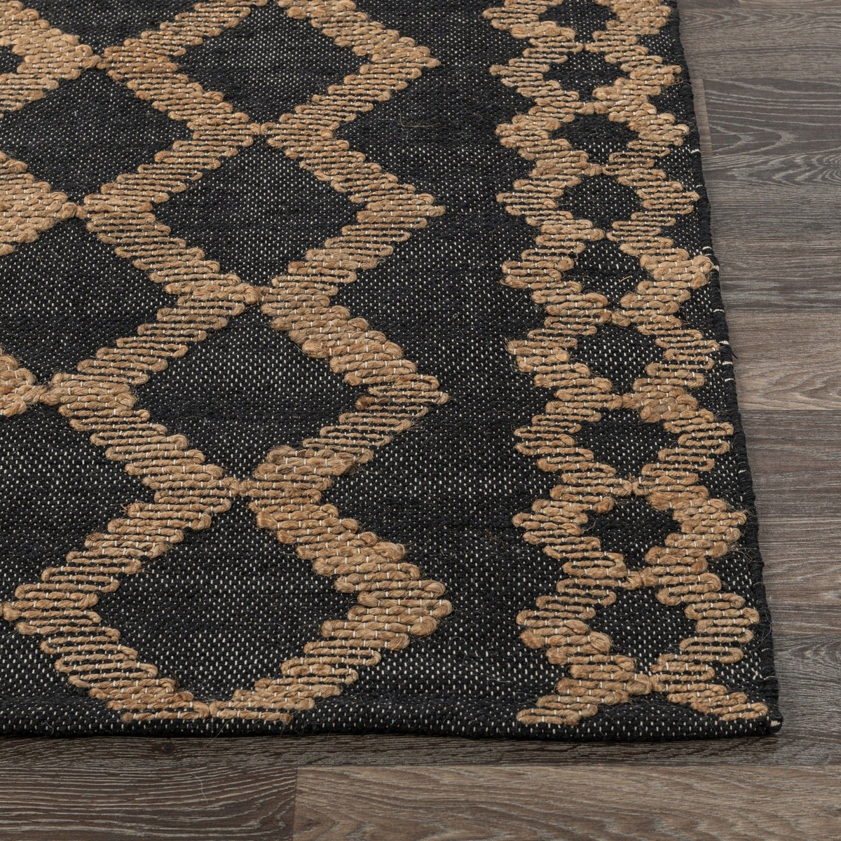 Corner detail of black-and-natural rug with raised diamond and zigzag stitching