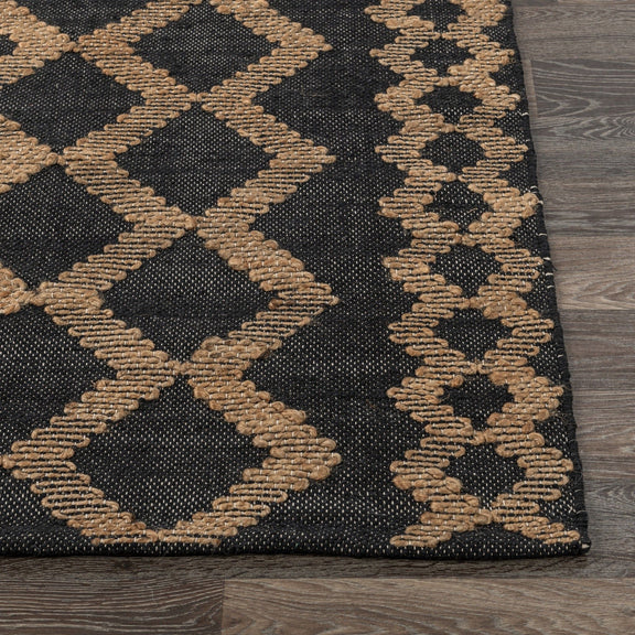 Corner detail of black-and-natural rug with raised diamond and zigzag stitching