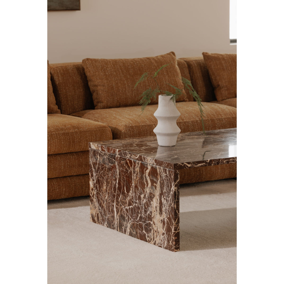 Marble coffee table corner view, red-brown veining and squared edges
