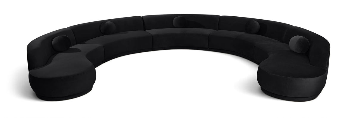Black velvet sectional sofa with rounded, button-tufted seat cushions.