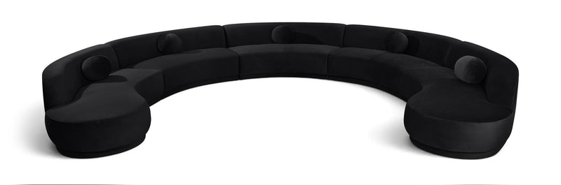 Black velvet sectional sofa with rounded, button-tufted seat cushions.