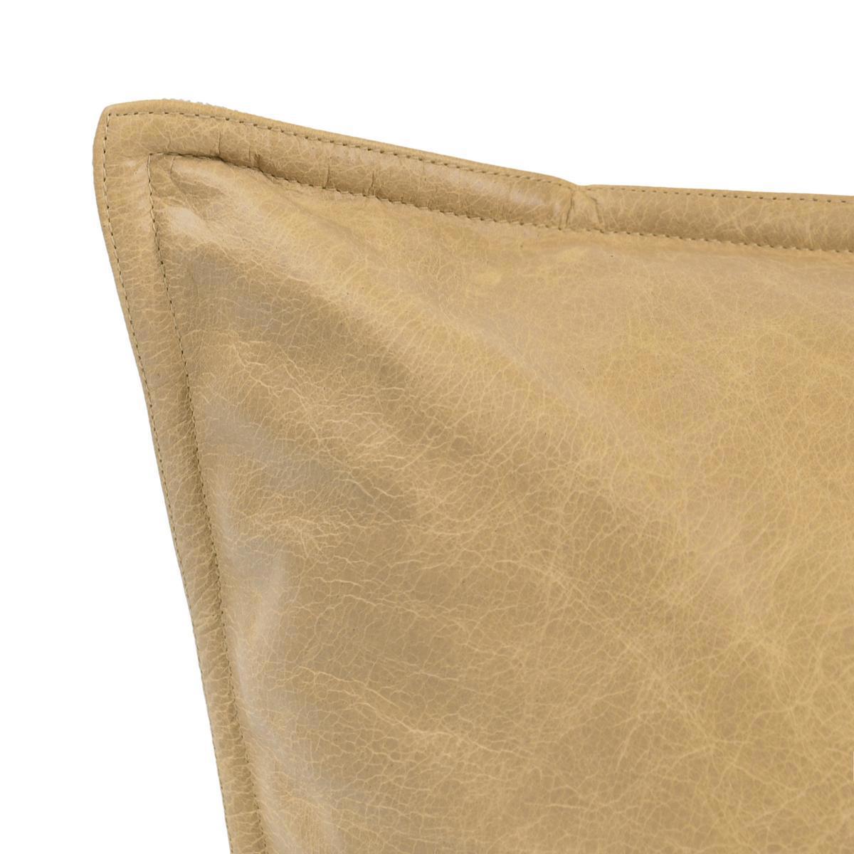 Tan leather pillow corner close-up with visible grain texture and seam.