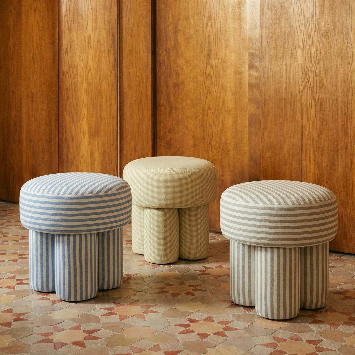 Three accent stools with round cushioned seats: light blue striped, beige solid, gray striped.