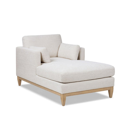 Beige fabric chaise lounge chair with padded back and ottoman-style base