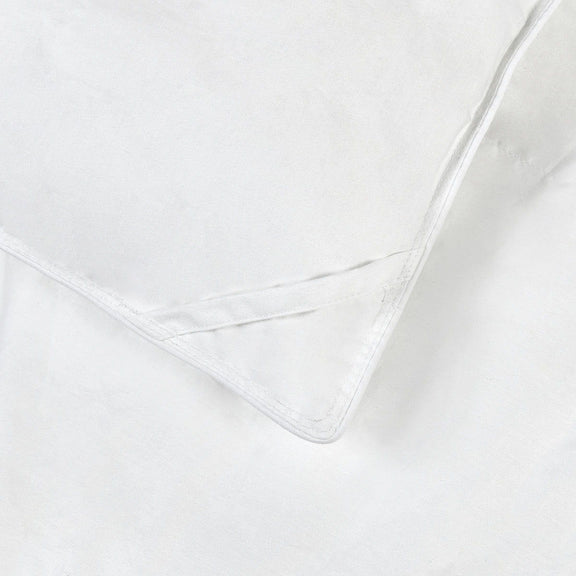 White down-alternative sham insert corner, visible edge stitching and piped trim