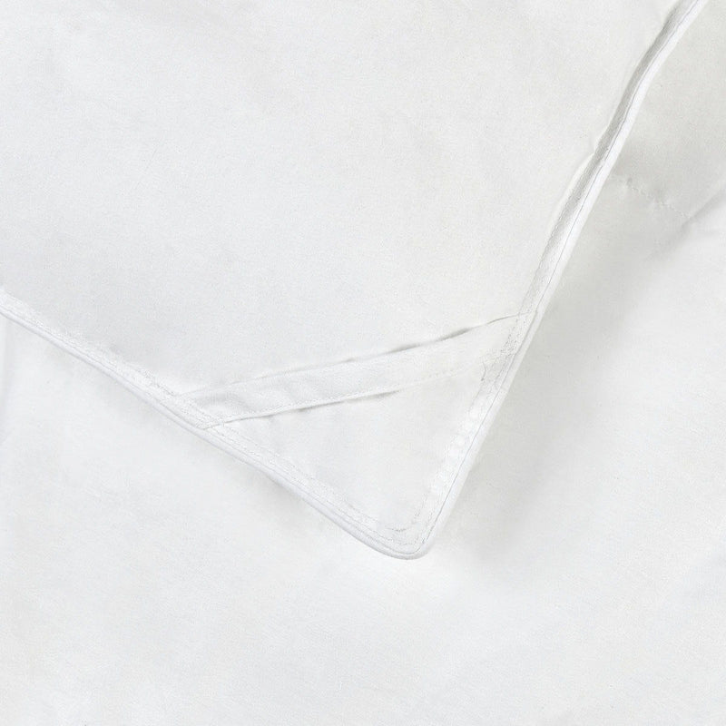 White down-alternative sham insert corner, visible edge stitching and piped trim