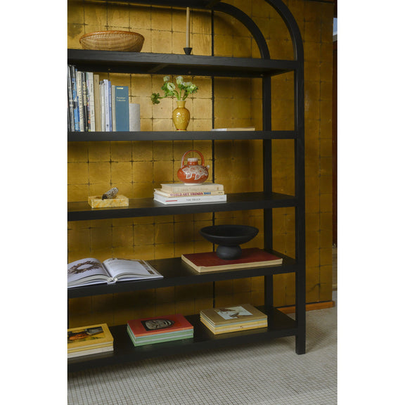 Black bookcase with arched frame, stocked shelves for books and decor