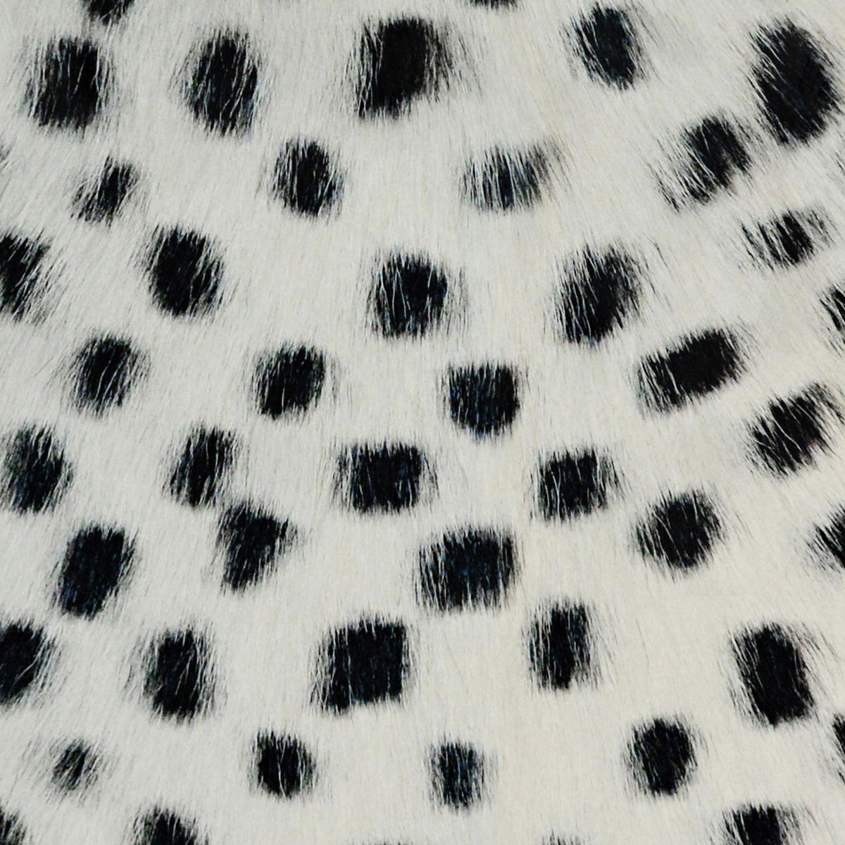 White fur pillow fabric with black dot pattern, close-up texture