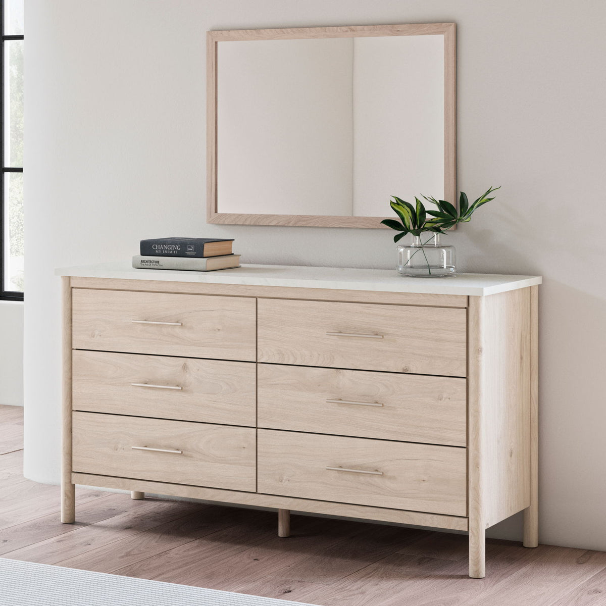 Rectangular bedroom mirror with tan wood frame above light wood dresser
