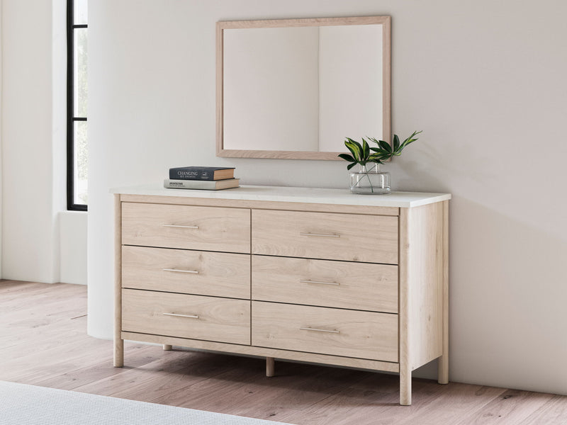 Rectangular bedroom mirror with tan wood frame above light wood dresser