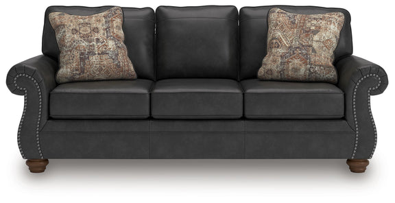 Dark gray sofa with square arms and two patterned accent pillows, stitched panel seats