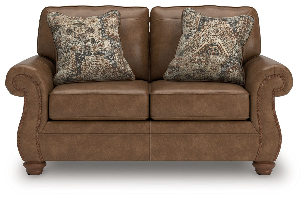 Dark brown loveseat with tufted arm details and two patterned accent pillows