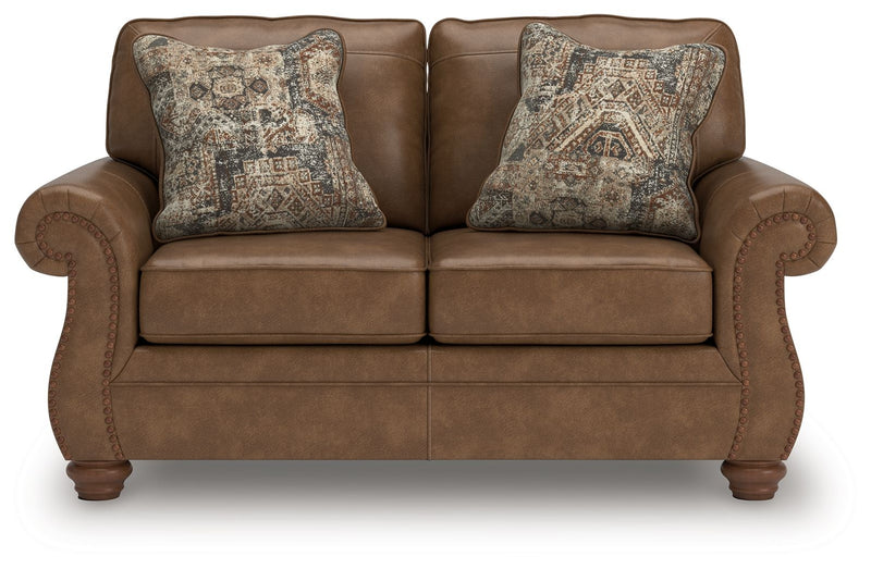 Dark brown loveseat with tufted arm details and two patterned accent pillows