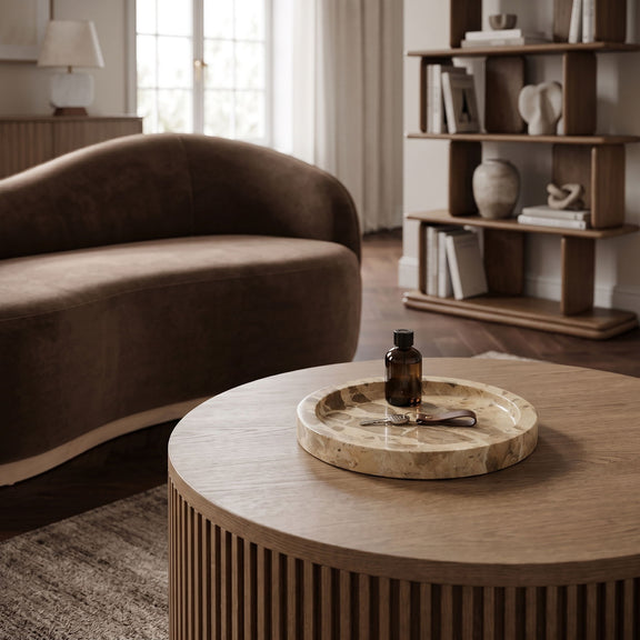 Round beige marble tray on table with shallow basin and stone veining