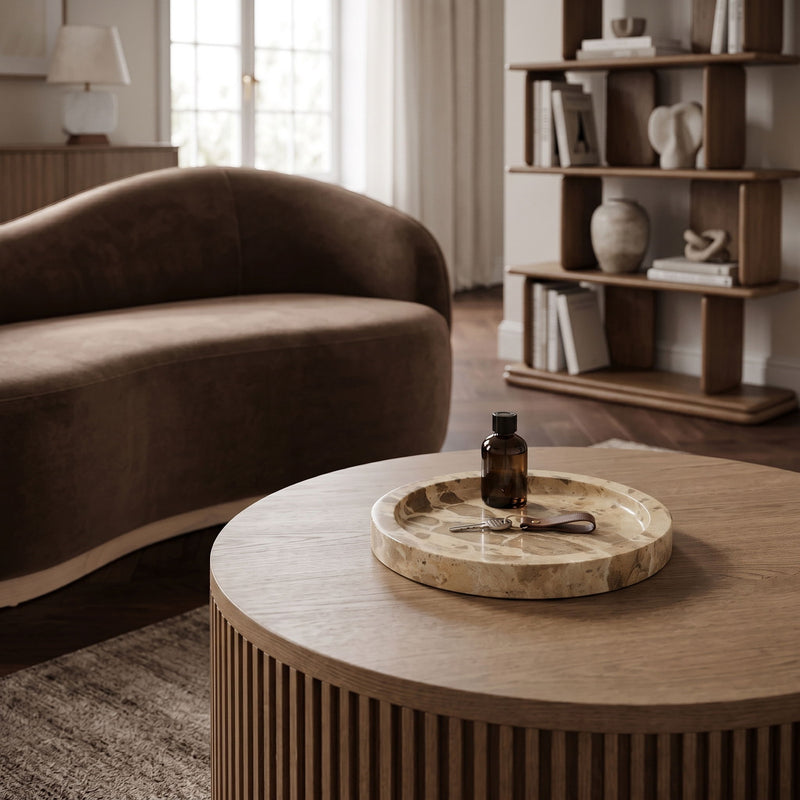 Round beige marble tray on table with shallow basin and stone veining