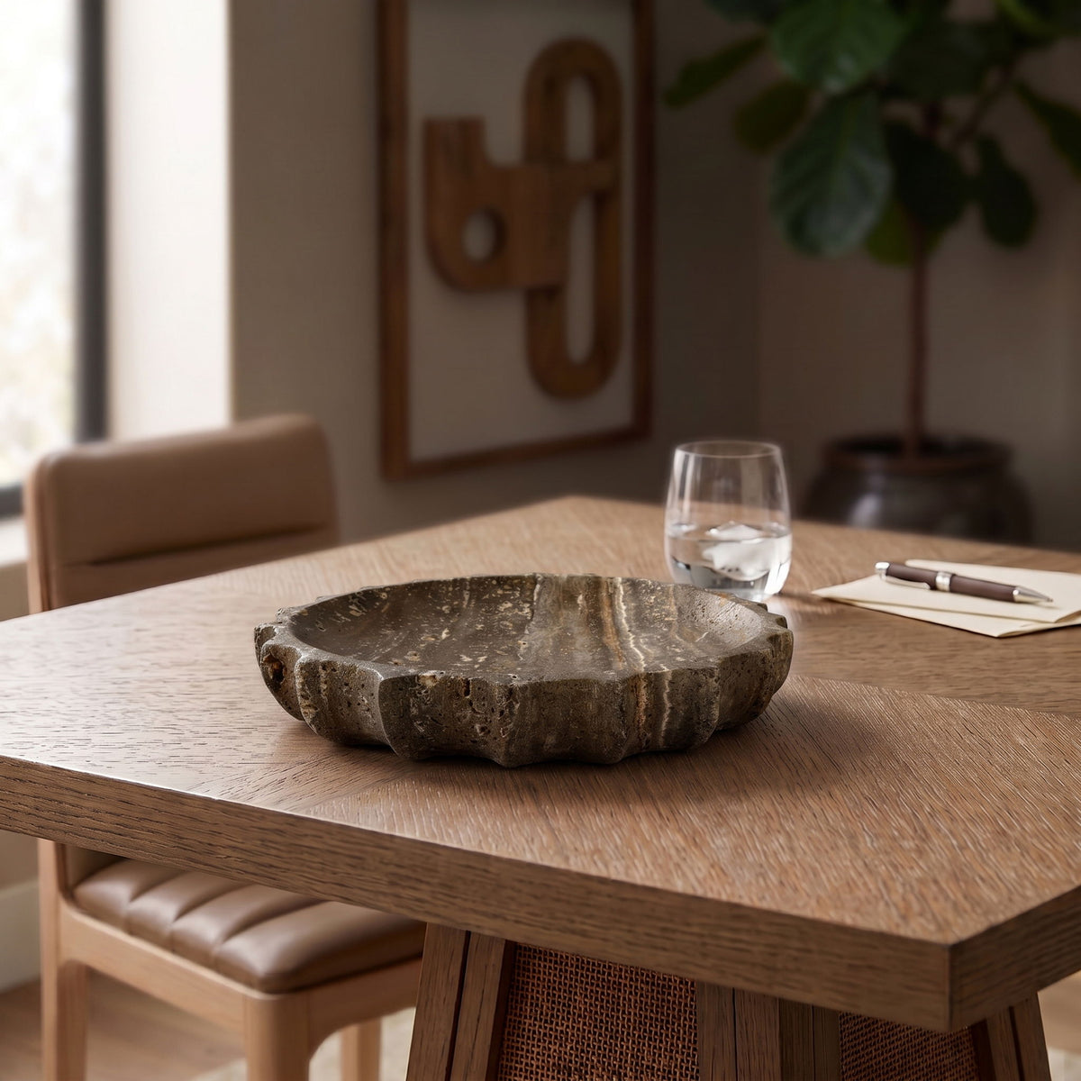 Gray travertine serving bowl on a wooden table, scalloped rim visible.