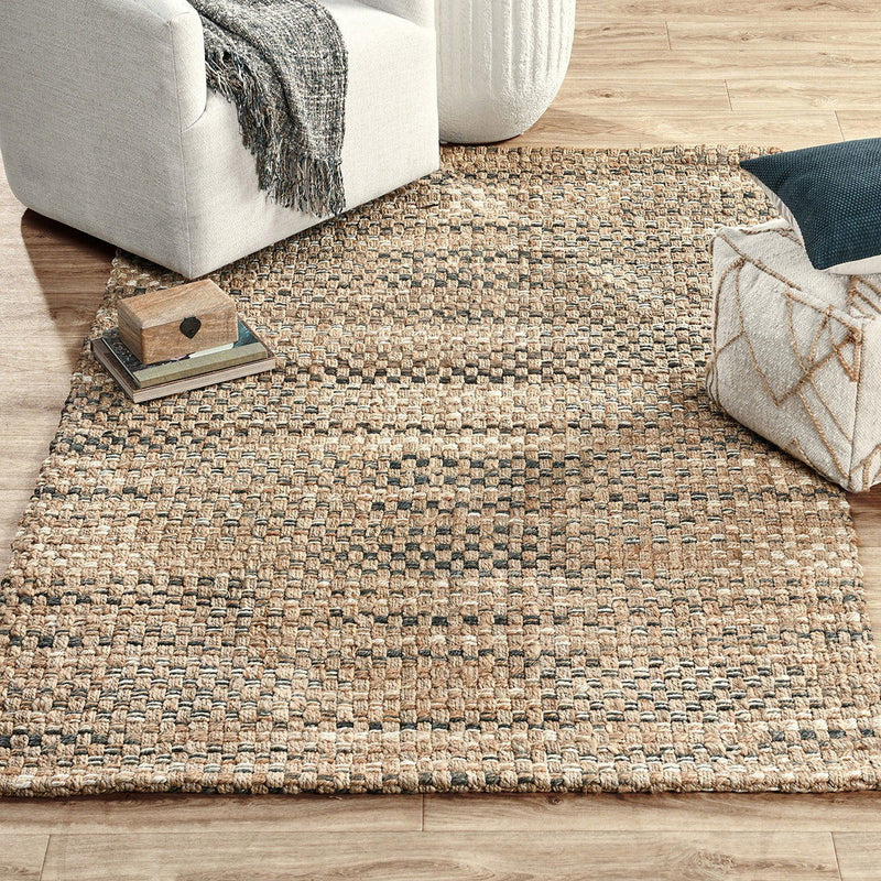 Light brown woven rug with bold horizontal stripes, styled on wooden floor with pillows