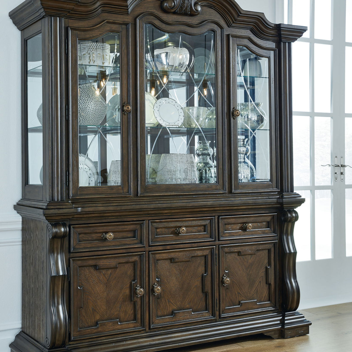 Dark brown dining buffet hutch with three glass doors and paneled cabinet base