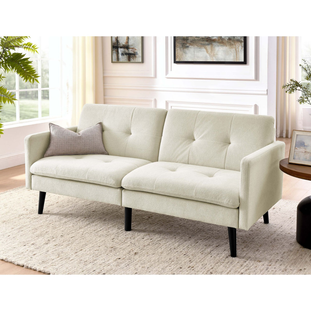 Light beige futon sofa with tufted back and seat cushions, shown in a living room