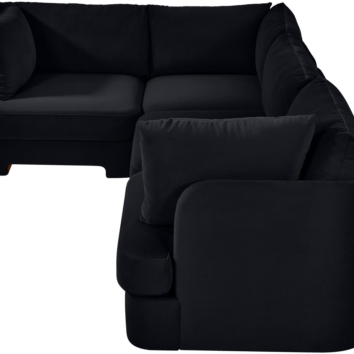Black velvet sectional sofa with curved armrests and a matching throw pillow