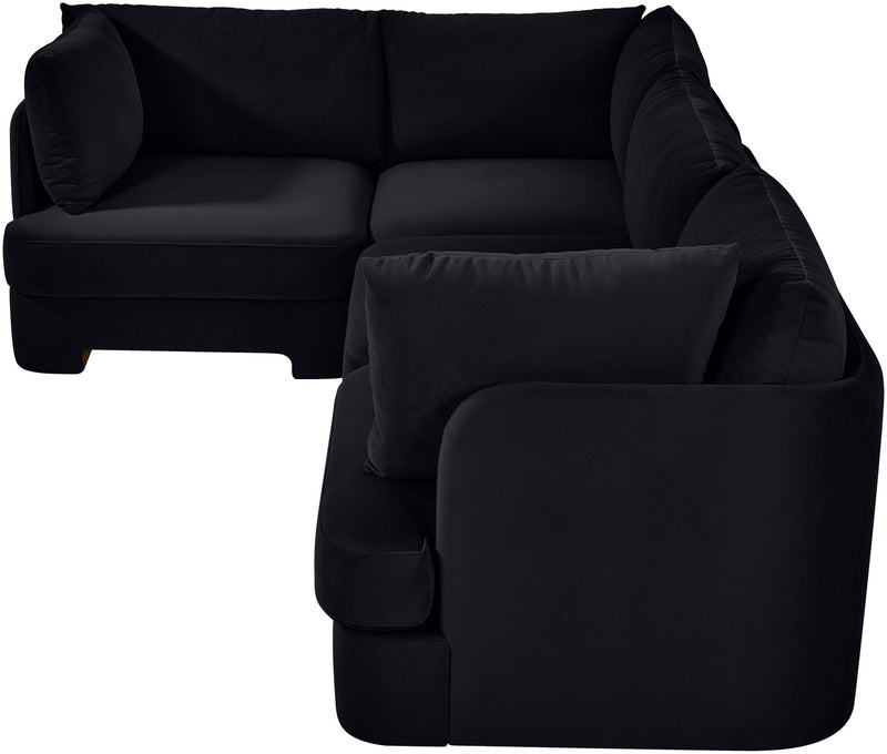 Black velvet sectional sofa with curved armrests and a matching throw pillow