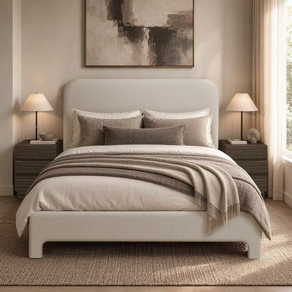 Light brown upholstered bed with pillows and layered bedding on slat base