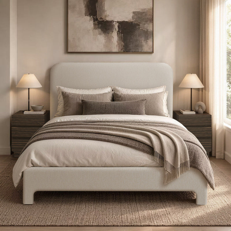 Light brown upholstered bed with pillows and layered bedding on slat base