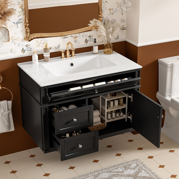 Black vanity with white sink, two drawers and open tip-out drawer and cabinet door showing storage.