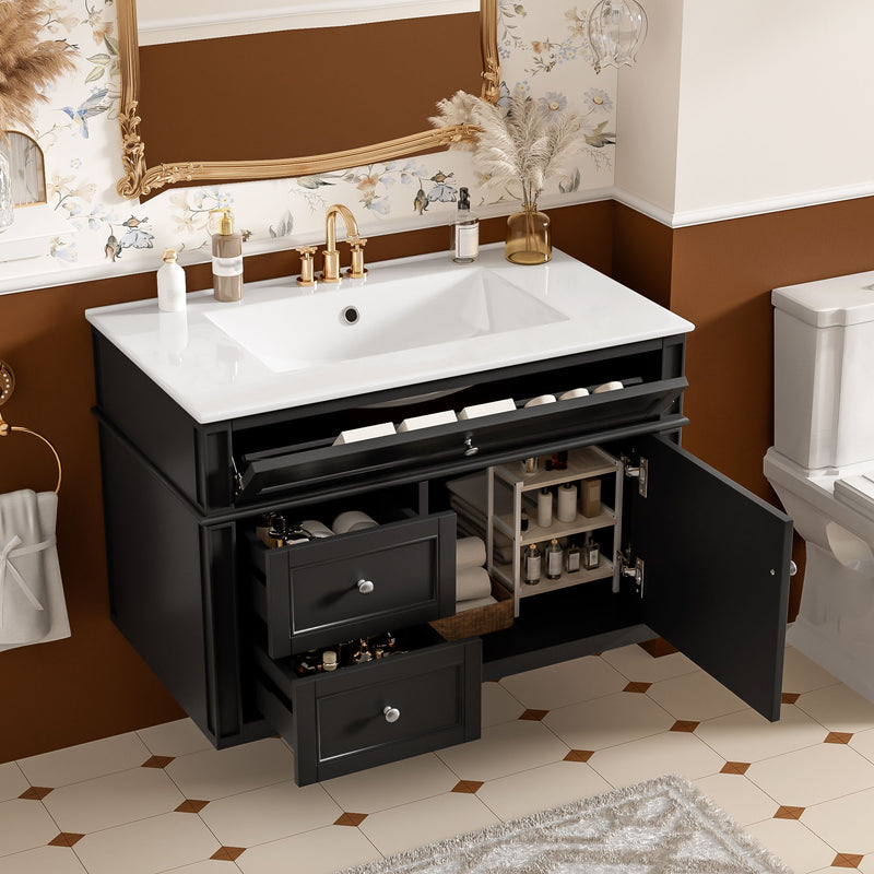 Black vanity with white sink, two drawers and open tip-out drawer and cabinet door showing storage.