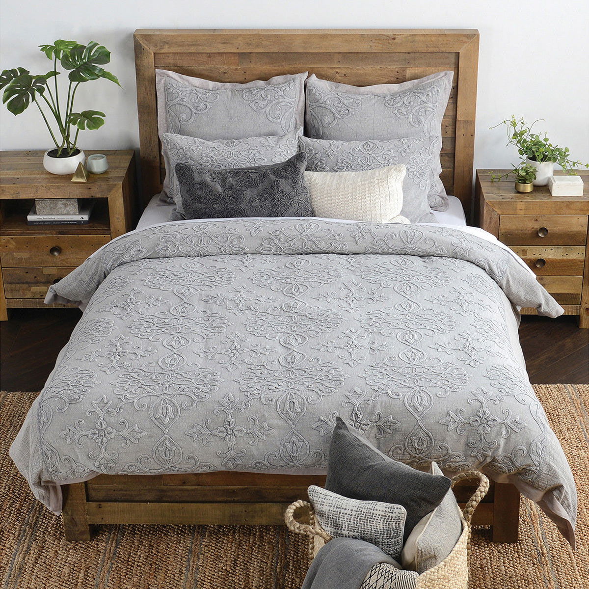 Gray embroidered sham pillows on bed with ornate scroll and floral patterns