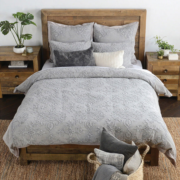 Gray embroidered sham pillows on bed with ornate scroll and floral patterns
