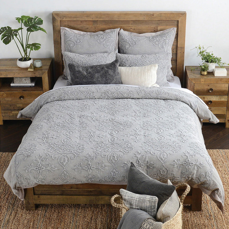 Gray embroidered sham pillows on bed with ornate scroll and floral patterns