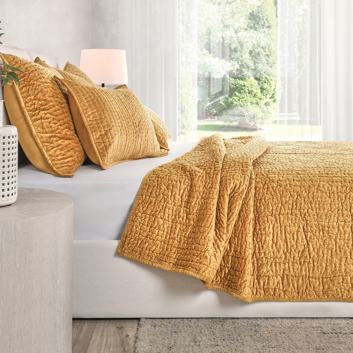 Golden yellow velvet quilt set with textured quilt and coordinating pillows on sofa.