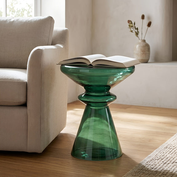 Green hourglass-shaped blown glass side table with open book on top.
