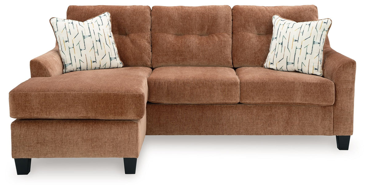 Clay brown sofa chaise with two patterned throw pillows and wide chaise cushion