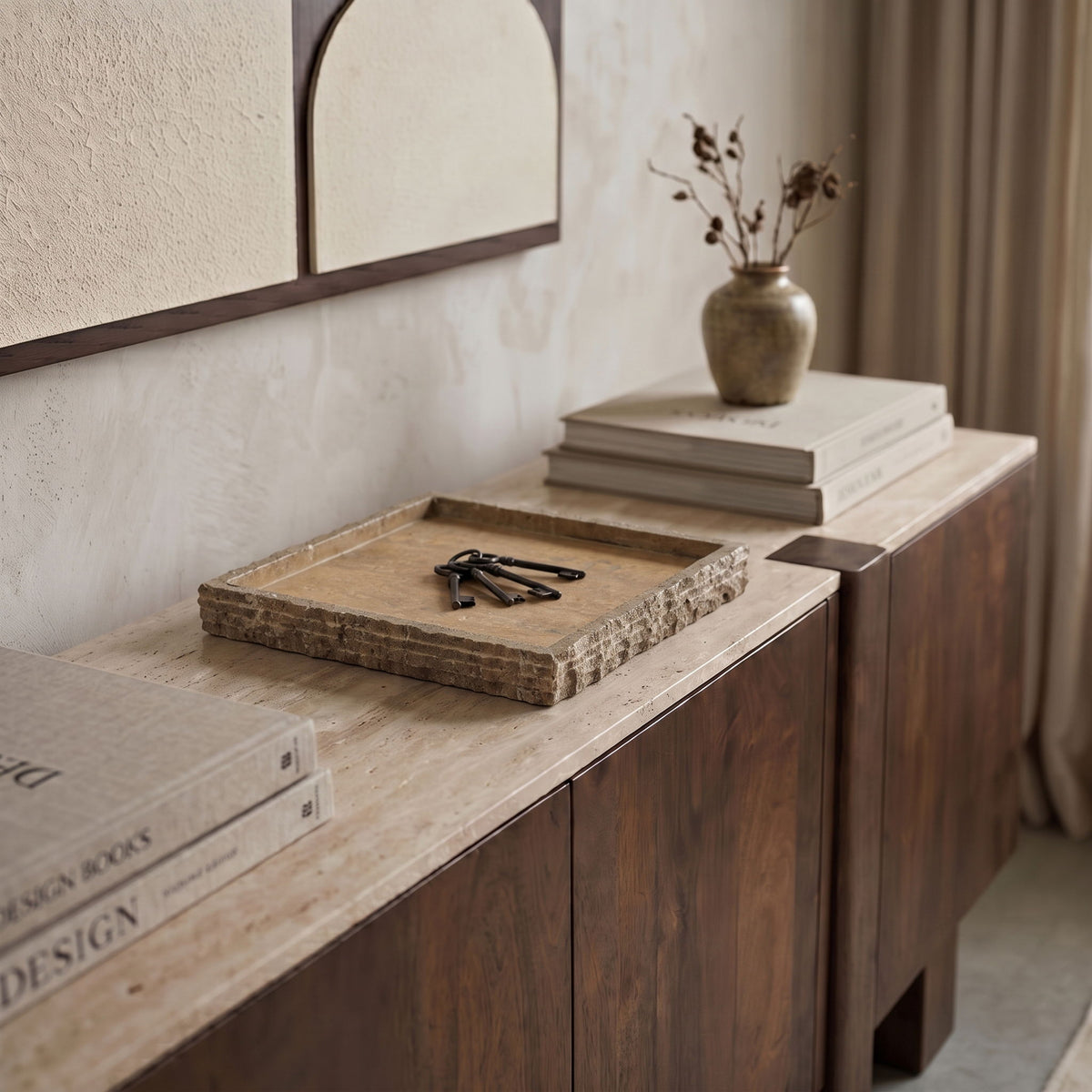 Beige marble tray on a countertop with raised rim and swirling light veining.