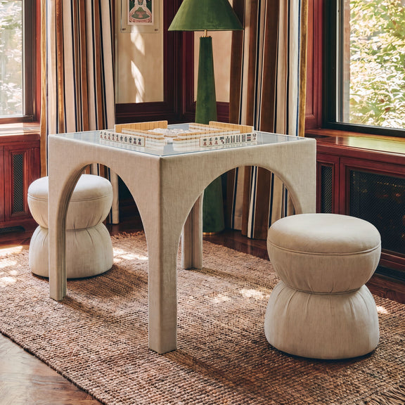 Beige ruched upholstered ottoman with rounded top and stacked cushioned base